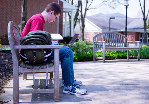 A student studies on a bench on the LBC Lancaster Campus