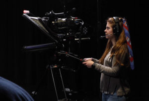 A woman operating a high quality video camera.