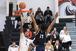 men's basketball player stretches to the rim of the basket to make the shot