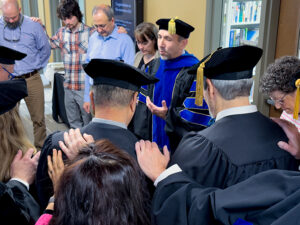Faculty, family and friends pray over doctoral students before the May 2023 graduation ceremony.
