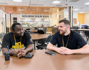 two LBC graduates who work at Water Street Mission talk together in the dining hall