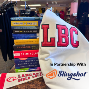 an LBC sweatshirt and pennant over a stack of books with slingshot logo
